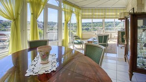 A dining area with a wooden table, chairs, and a view of the landscape through large windows. - Maison 350 m Centre, Chambres Calmes, Spacieuses (Angoulême)