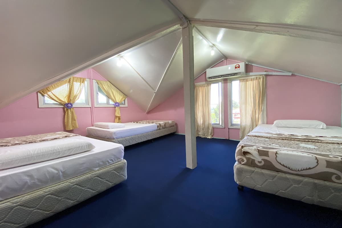 Una habitación con dos camas, una ventana con cortinas amarillas, un equipo de aire acondicionado y una alfombra azul.