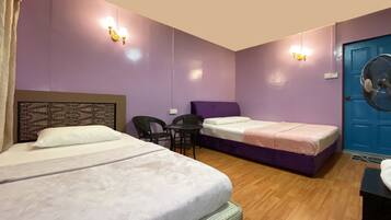 A room with two beds, a table, chairs, and a blue door.