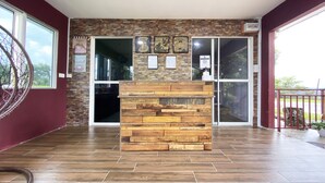 A reception area with a wooden block counter, stone wall, and large glass doors leading to an outdoor area. - Hotel O Pogimpaan Homestay (Ranau)