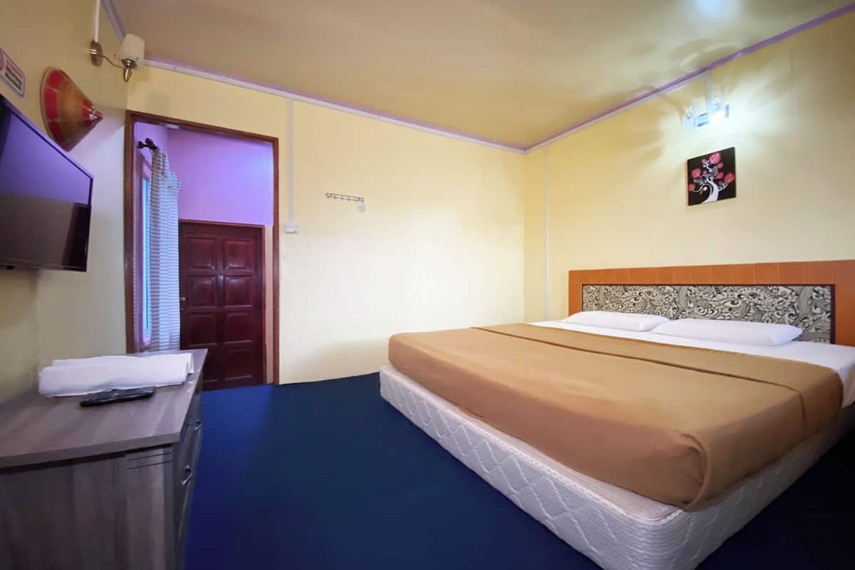 Una habitación de hotel con cama, escritorio, televisor y puerta.