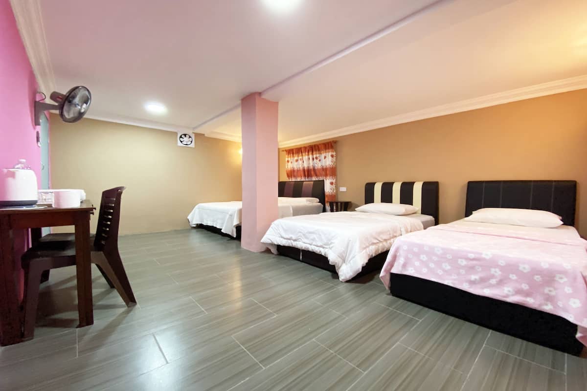 Una habitación de hotel con tres camas, un escritorio y una silla, y un ventanal con cortinas.