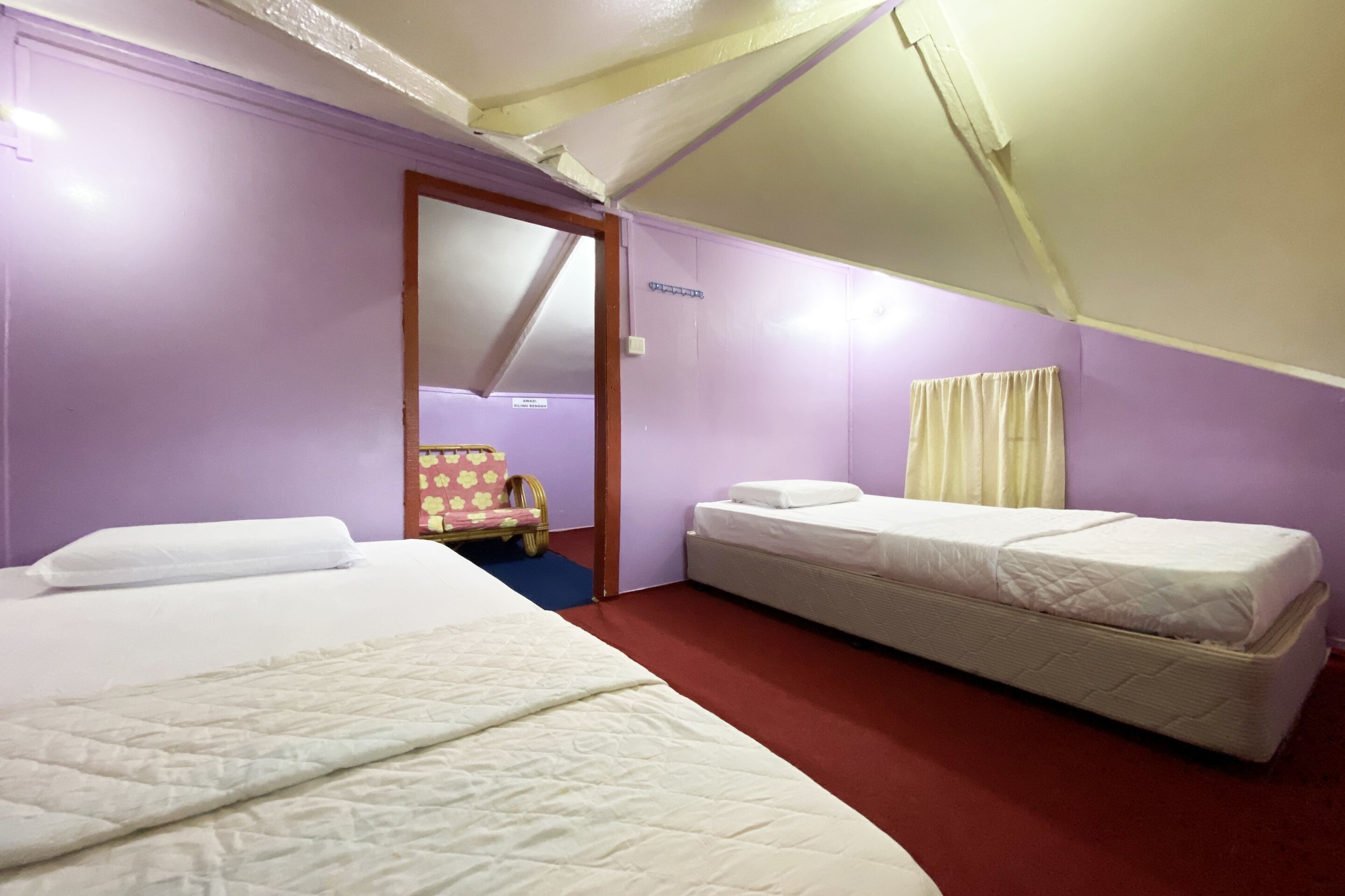 A room with two beds, a chair, and a door.
