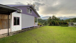 A house with a purple exterior, a stone foundation, and a grassy yard. - Hotel O Pogimpaan Homestay (Ranau)