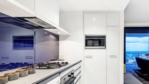 Una cocina moderna con estufa a gas, horno, microondas y vista a la ciudad a través de un ventanal amplio.