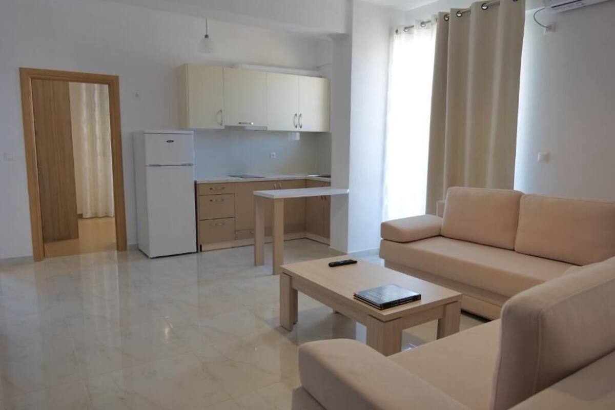 Een modern appartement met een kitchenette, een bank, een salontafel en een deur naar een andere kamer.