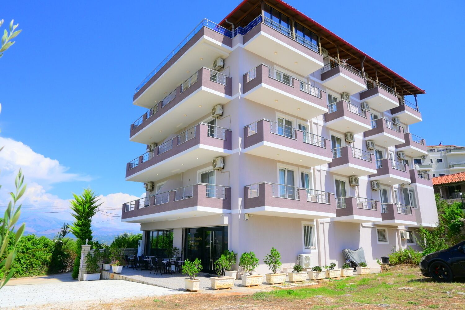 A multi-story building with balconies, air conditioning units, and a small outdoor seating area.