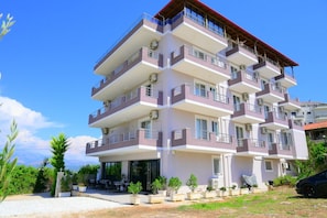 A multi-story building with balconies, air conditioning units, and a small outdoor seating area. - Golden Berden Boutique Hotel (Sarandë)
