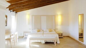 Een slaapkamer met een groot bed, nachtkastjes, een bankje, een bureau en een spiegel.