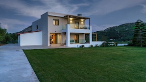 Una casa moderna de dos pisos con balcón, entrada para vehículos y césped cuidado.