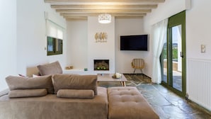Una sala de estar moderna con un sofá, una chimenea, un televisor y vistas a través de un ventanal.