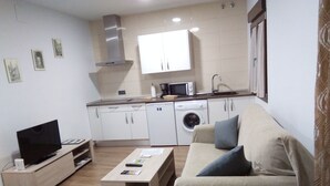 Ein gemütlicher Wohnraum mit Sofa, Couchtisch, Fernseher, Waschmaschine und Mikrowelle.