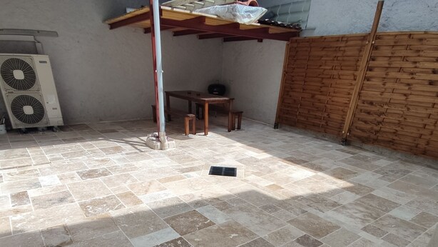 A room with a tiled floor, a standing fan, a wooden table, and a bench. - Logement Entièrement Neuf Tout Confort (Lucey)