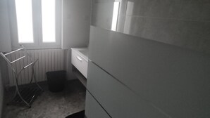 A bathroom with a window, a towel rack, a sink, and a trash bin. - Logement Entièrement Neuf Tout Confort (Lucey)