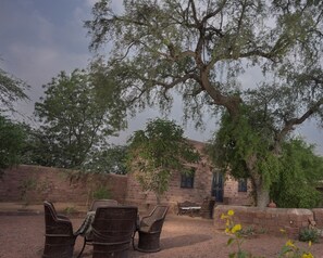 Relax in a serene outdoor seating area surrounded by lush greenery and a brick wall.