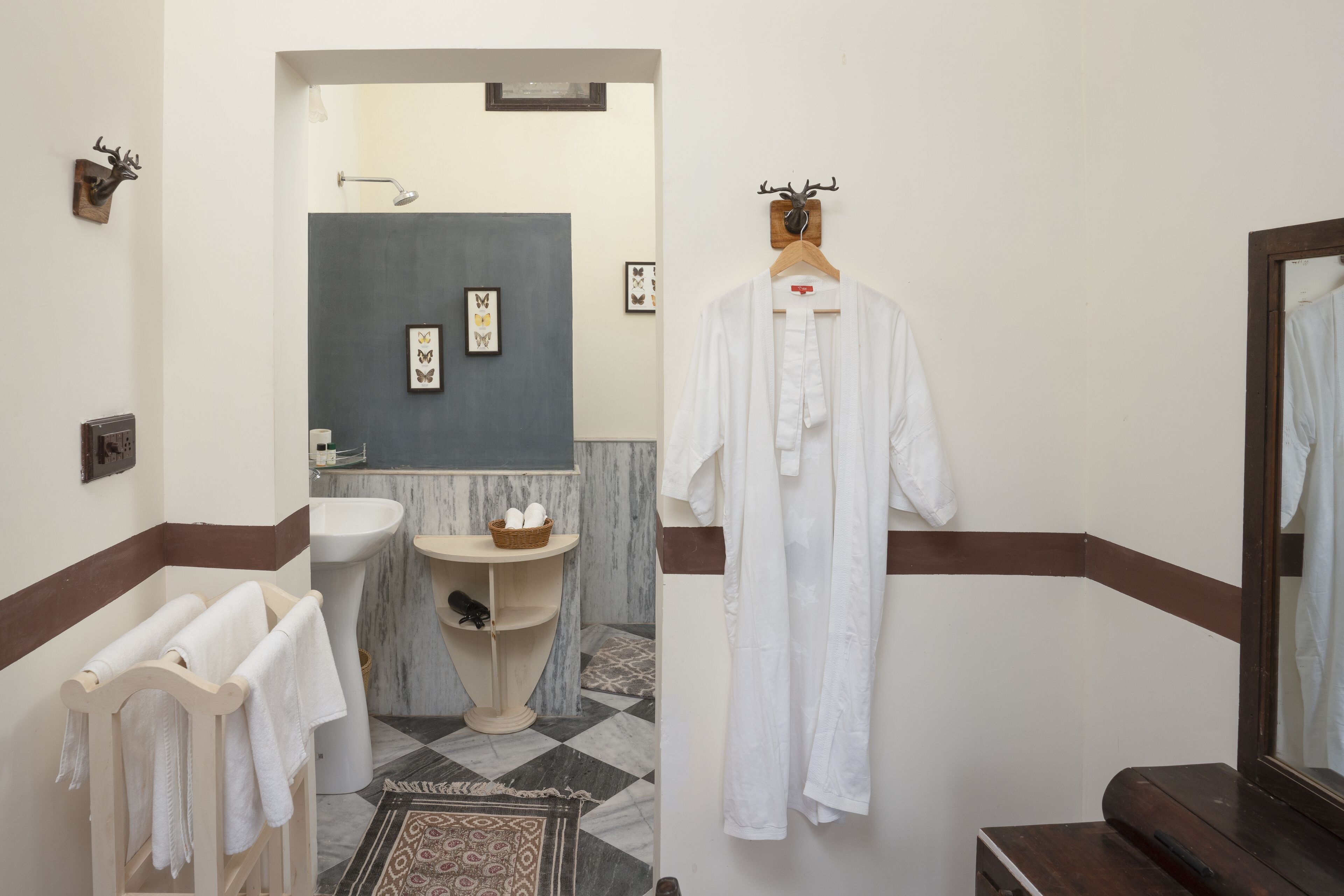 Un baño con lavamanos, espejo y perchero para toallas.