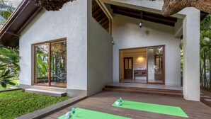 Une maison moderne dotée de grandes portes vitrées, d’une terrasse en bois et de tapis verts.