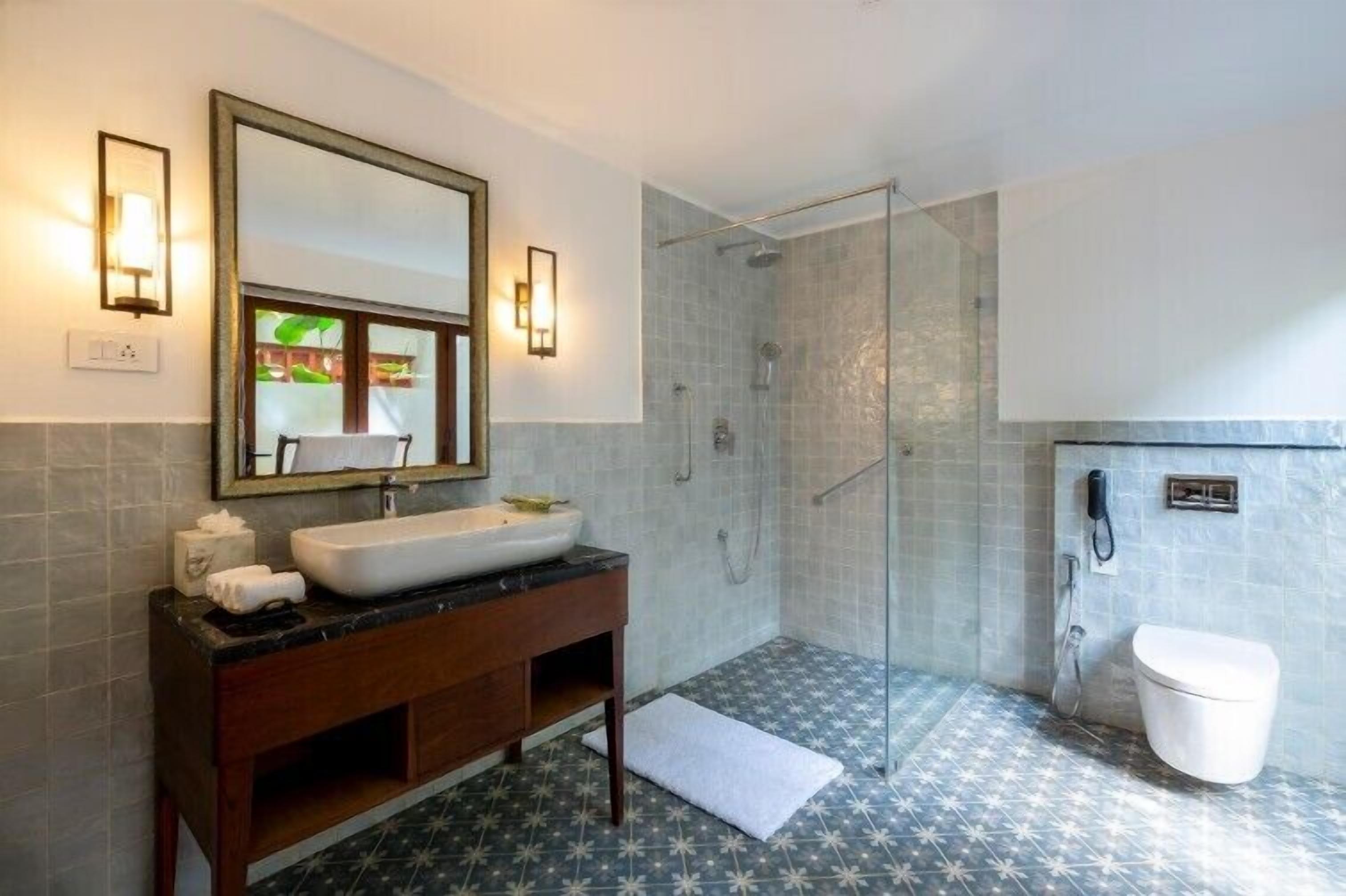 Une salle de bain avec un grand miroir, un lavabo, une douche et des toilettes.