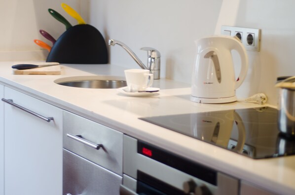 A modern kitchen with a stainless steel sink, a white kettle, and a knife block with colorful handles. - Fantastic and Bright Apartment in the Heart of Gothic area 10 min from the beach (Barcelona)