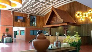 Un hall d’entrée avec un comptoir de réception en bois, un grand vase et des plantes en pot.