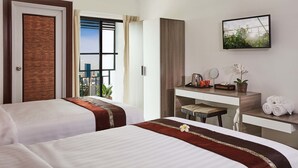 Une chambre d’hôtel avec deux lits, un bureau avec un miroir, une petite table avec une bouilloire, des tasses et une plante.