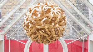 A room with a large wooden spherical light fixture, white walls, and a red patterned carpet.