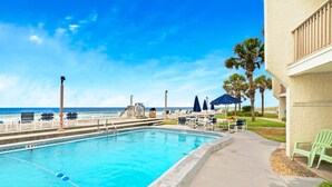 A swimming pool with a view of the ocean, lounge chairs, and umbrellas. - ☀️Beach Front-Pool + HotTub-Latitude 29 #2☀️ (Panama City Beach)