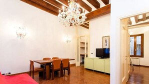 A room with a dining table, chairs, a chandelier, a television, and a cabinet. - Signorile su Corte Veneziana (Venezia)