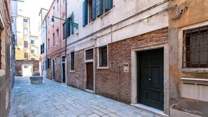 A narrow cobblestone street flanked by historic buildings with brick facades and traditional shutters. - Signorile su Corte Veneziana (Venezia)