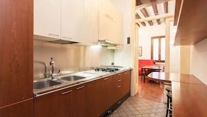 A kitchen with wooden cabinets, a stainless steel sink, and a gas stove. - Signorile su Corte Veneziana (Venezia)