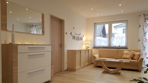 A modern living room with a wooden floor, a white wardrobe, a beige sofa, and a glass coffee table. - Vacation home MoselCharme "Burgblick" (Alken)