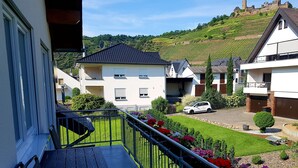 A residential area with a balcony, a white building, and a car parked on the street. - Vacation home MoselCharme "Burgblick" (Alken)