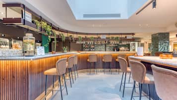A modern bar area with a curved counter, bar stools, and a variety of bottles and glasses.