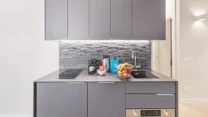 Una cocina moderna con gabinetes grises, encimera negra y protector contra salpicaduras de piedra.