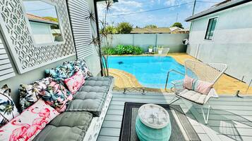 Relax by the pool surrounded by a comfortable seating area with a sofa, chair, and ottoman.