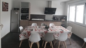 A compact kitchen with a refrigerator, microwave, and oven. A dining table with chairs is set up in the center. - Brand new house with all comforts (Lucey)