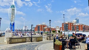 A waterfront promenade with a distinctive sail-shaped building, stone seating areas, and a variety of dining establishments. - One bedroom balcony apartment with allocated parking close to Gunwharf Quays (Portsmouth)