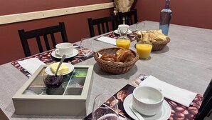 A breakfast table set with coffee cups, a basket of croissants, juice, and a bottle of water. - Chambre Zen (AUTIGNAC)