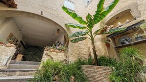 A courtyard with a staircase leading to a door, surrounded by plants and a stone wall. - Chambre Zen (AUTIGNAC)