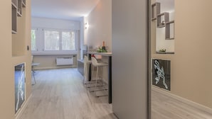 Een moderne keuken met witte barstoelen, een inbouw kookeiland, en een neonbord aan de muur.