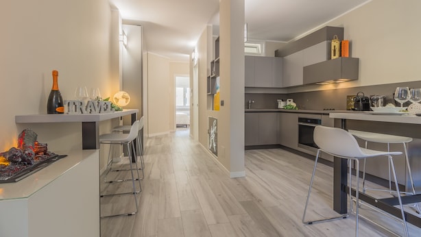 Een moderne keuken met een centraal eiland, barstoelen en een wijnrek.