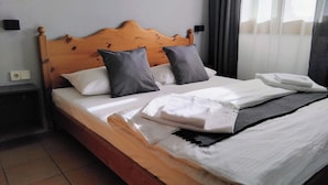 A neatly made bed with a wooden headboard, white and gray pillows, and a folded white towel.