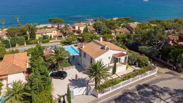 Uma área residencial costeira com piscina, casas com telhados vermelhos e vista para o mar.