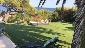 Uma área de pátio com gramado, uma cadeira de descanso e um sofá.