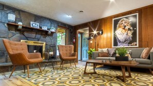 A cozy living room with a stone wall, a fireplace, and a large poster. - THE DOGWOOD @ DOLLYS DRIVE * Wifi Grill Woods Mtns (Sevierville)