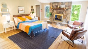 A bedroom with a bed, a stone fireplace, a window, and a seating area with a chair. - THE IRIS @ DOLLYS DRIVE * Wifi Grill Woods Mtns (Sevierville)