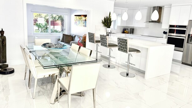 A modern kitchen with white cabinetry, stainless steel appliances, and pendant lighting. - Luxury heated salt water pool, Grill BBQ Serenity Oasis  (Miami)