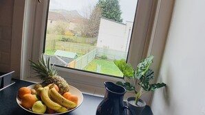A kitchen counter with a fruit bowl containing bananas, oranges, and a pineapple. There is a black pitcher and a potted plant on the counter. - Maria - Nice quiet city center apartment. (Edinburgh)