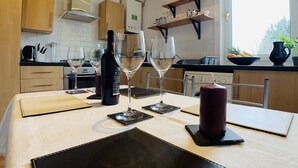 A modern kitchen with a dining table set for two, featuring wine glasses, a bottle, and a candle. - Maria - Nice quiet city center apartment. (Edinburgh)