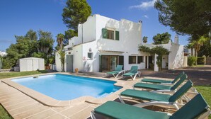 En modern villa med pool, utomhusmöbler och en trädgård.